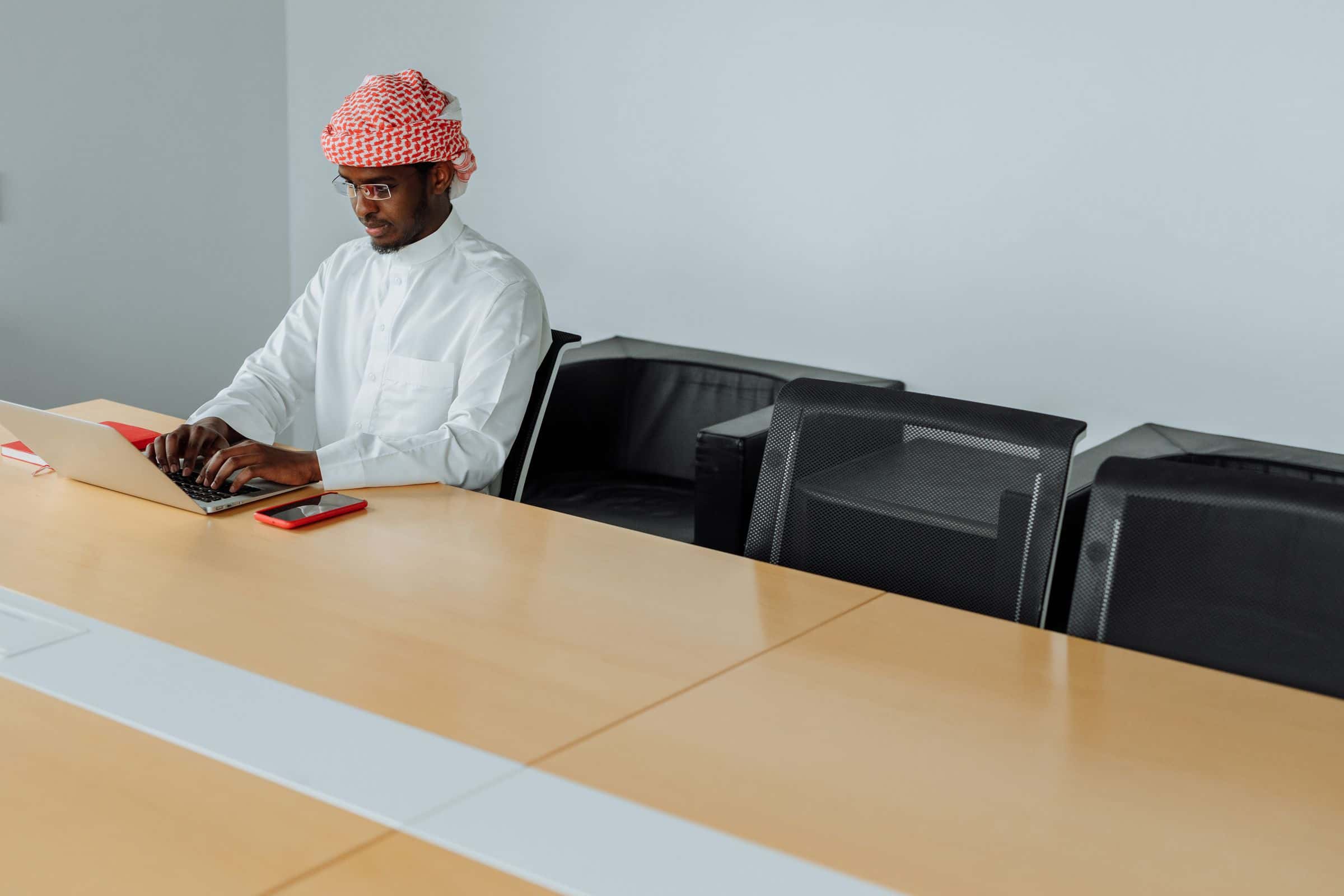 Gulf sales manager using a laptop and phone to manage customers in the Sultanate of Oman
