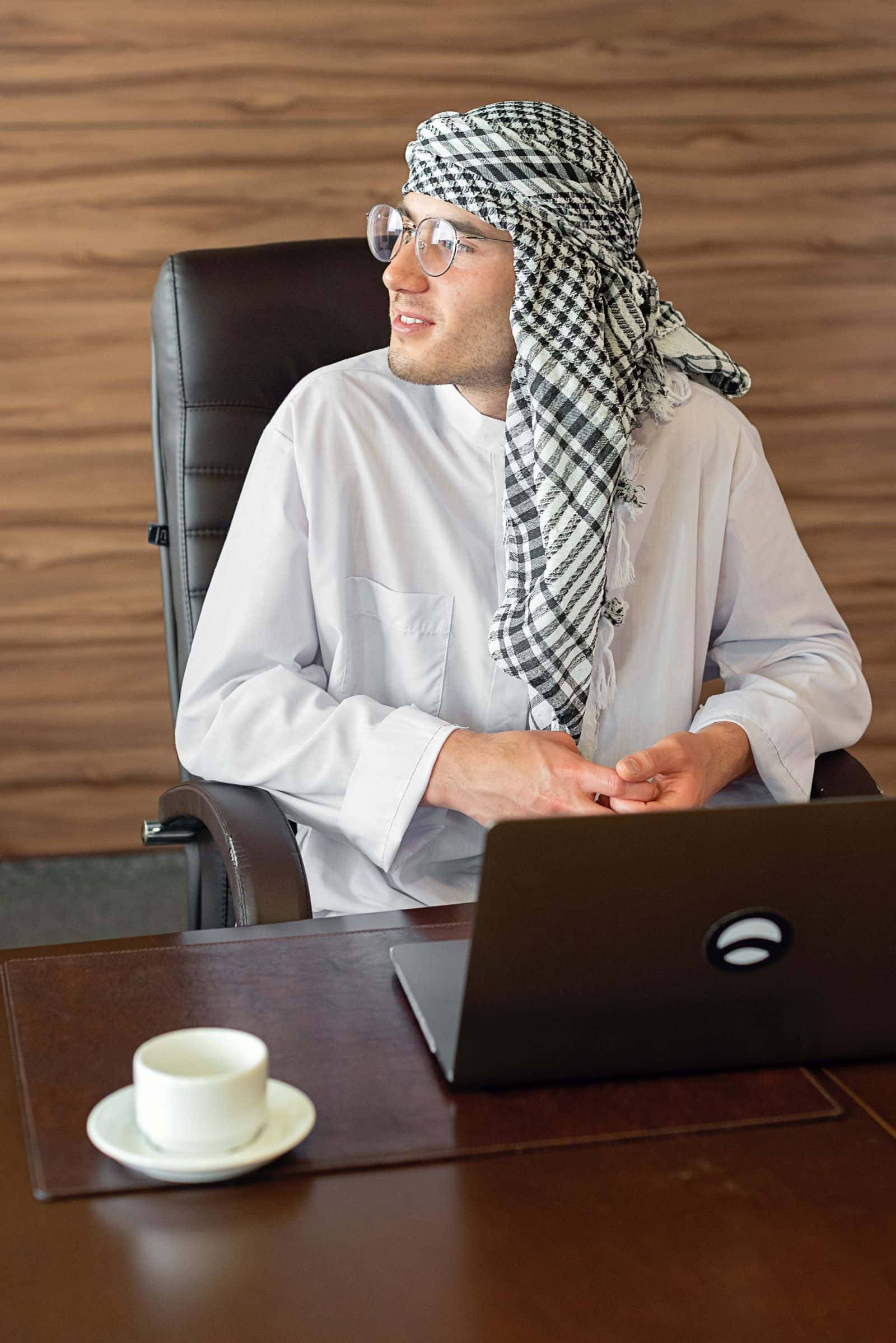 Gulf sales manager using a laptop and phone to manage customers in the Sultanate of Oman