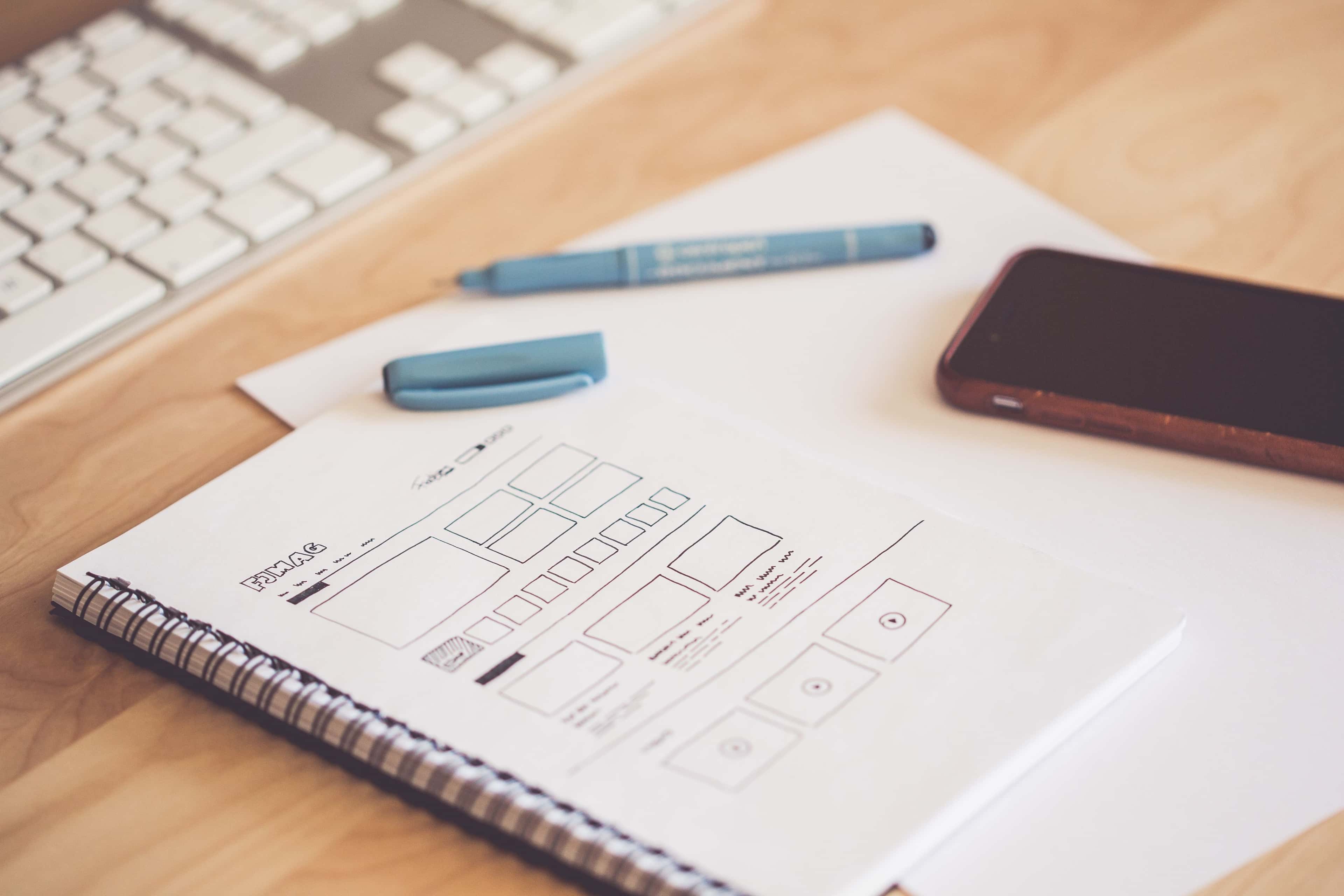 Pen and smartphone on a paper plan for preparing a PRD