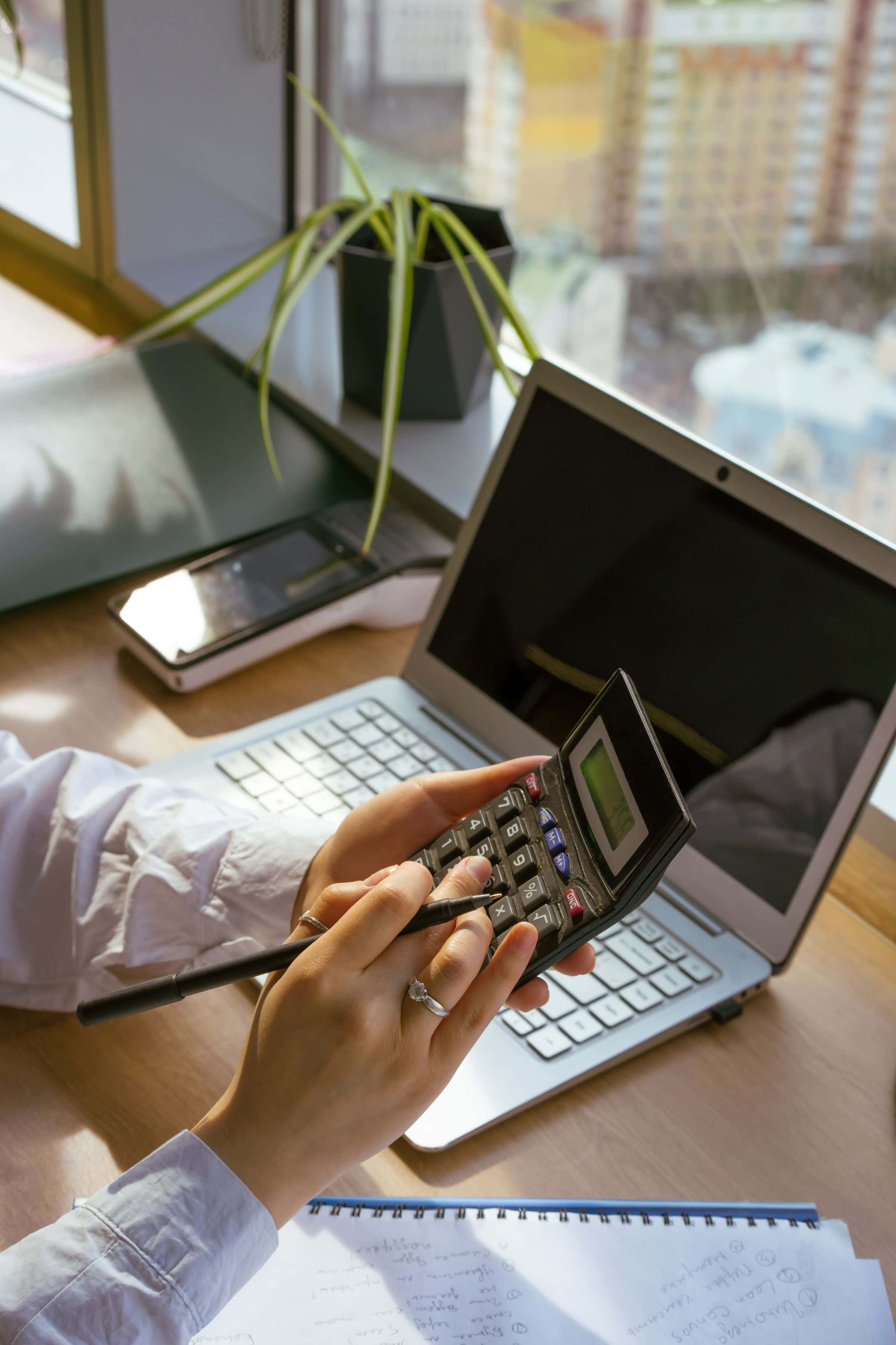 Business owner calculating a website design budget in the Sultanate of Oman with a laptop and calculator