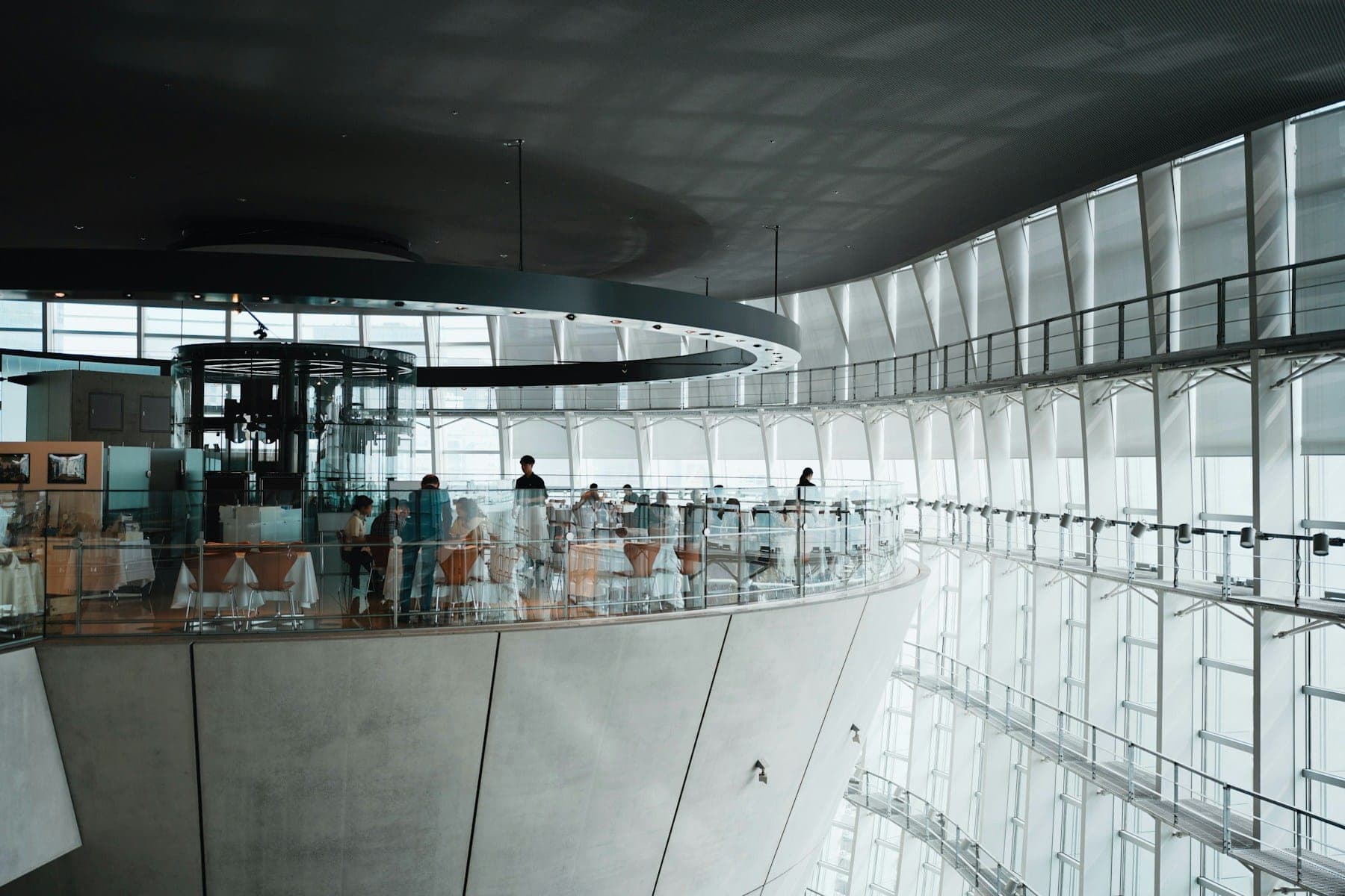 The curved glass atrium of a modern office building, its walkways wrapping a single open core.
