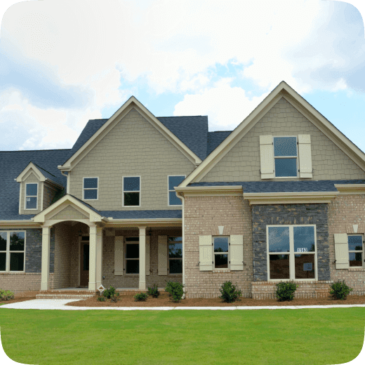 A two-storey brick-and-shingle house with a columned porch, set back behind a wide lawn.