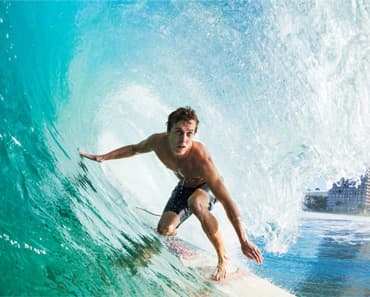 A surfer crouching inside the barrel of a breaking turquoise wave.
