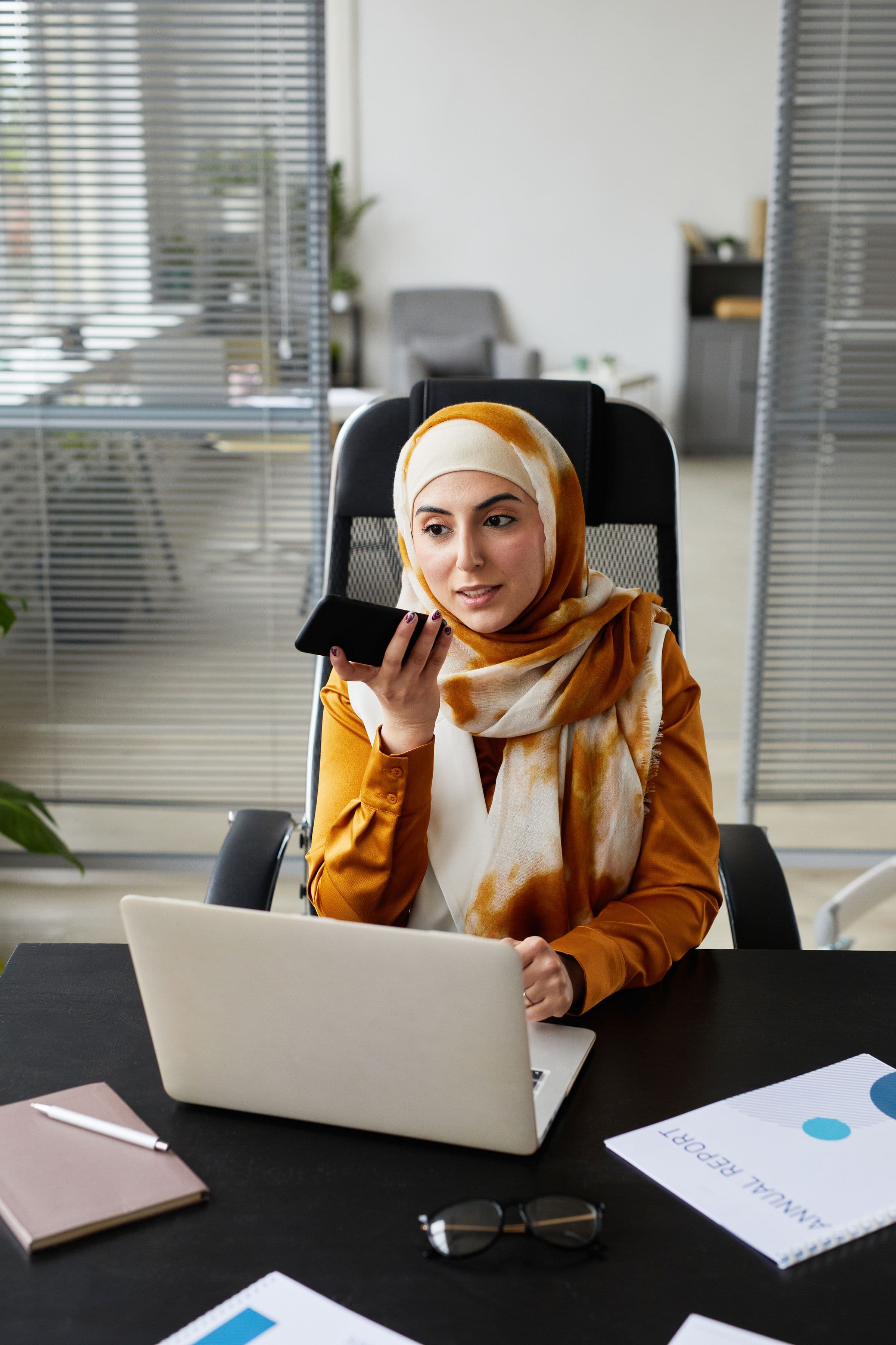 Arab businesswoman using a phone and laptop to choose a Gulf app development company