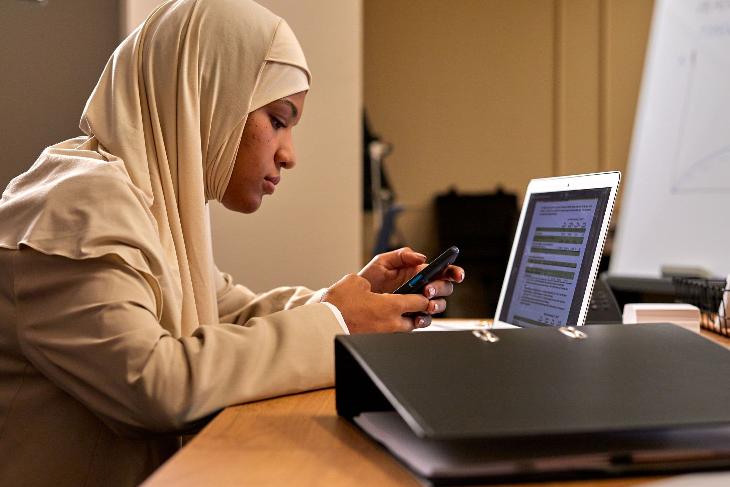 Arab businesswoman using a smartphone and laptop to manage digital customer conversations