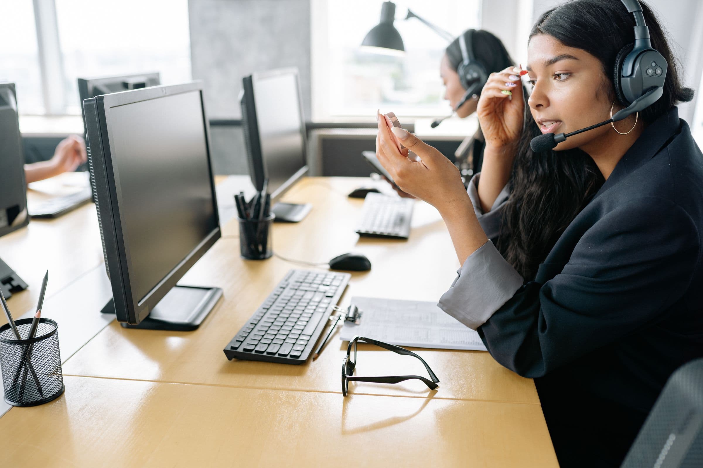 Arab woman in a headscarf using a laptop and headset in AI-assisted customer service