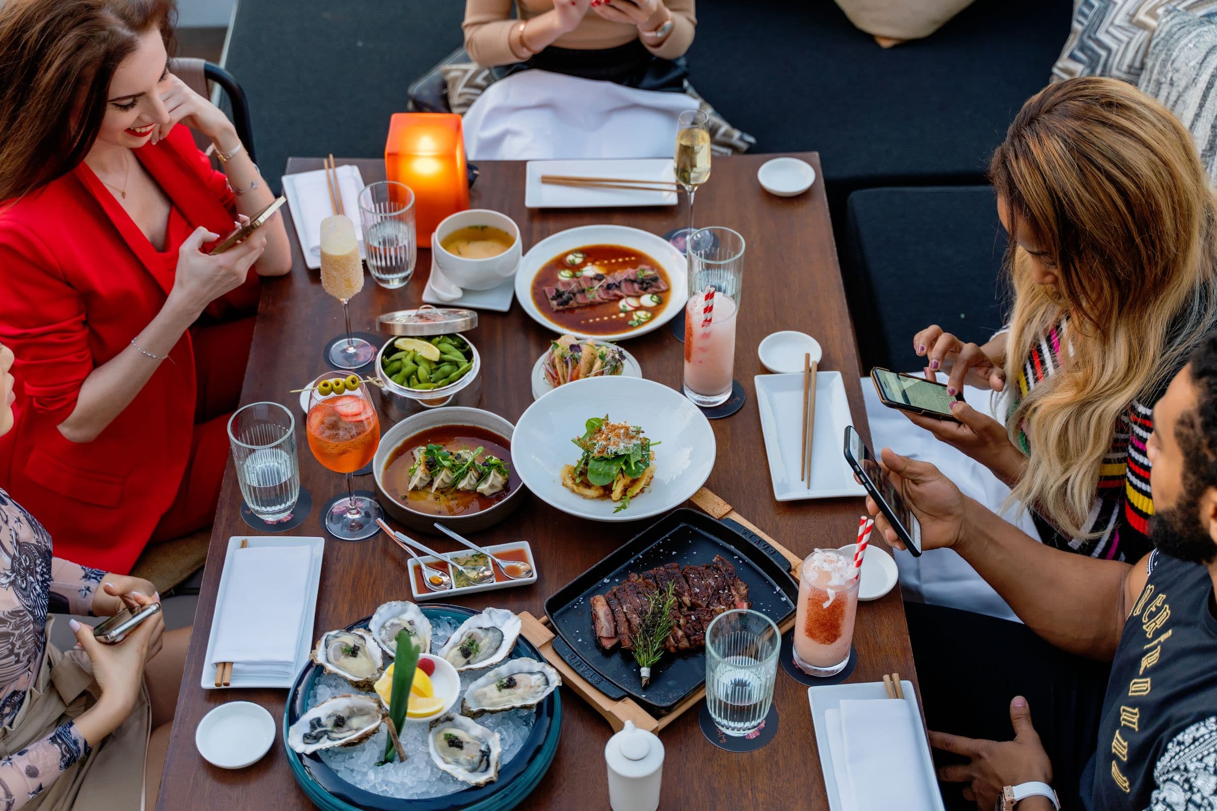 Diners in a Dubai restaurant using smartphones around a table to open a QR menu