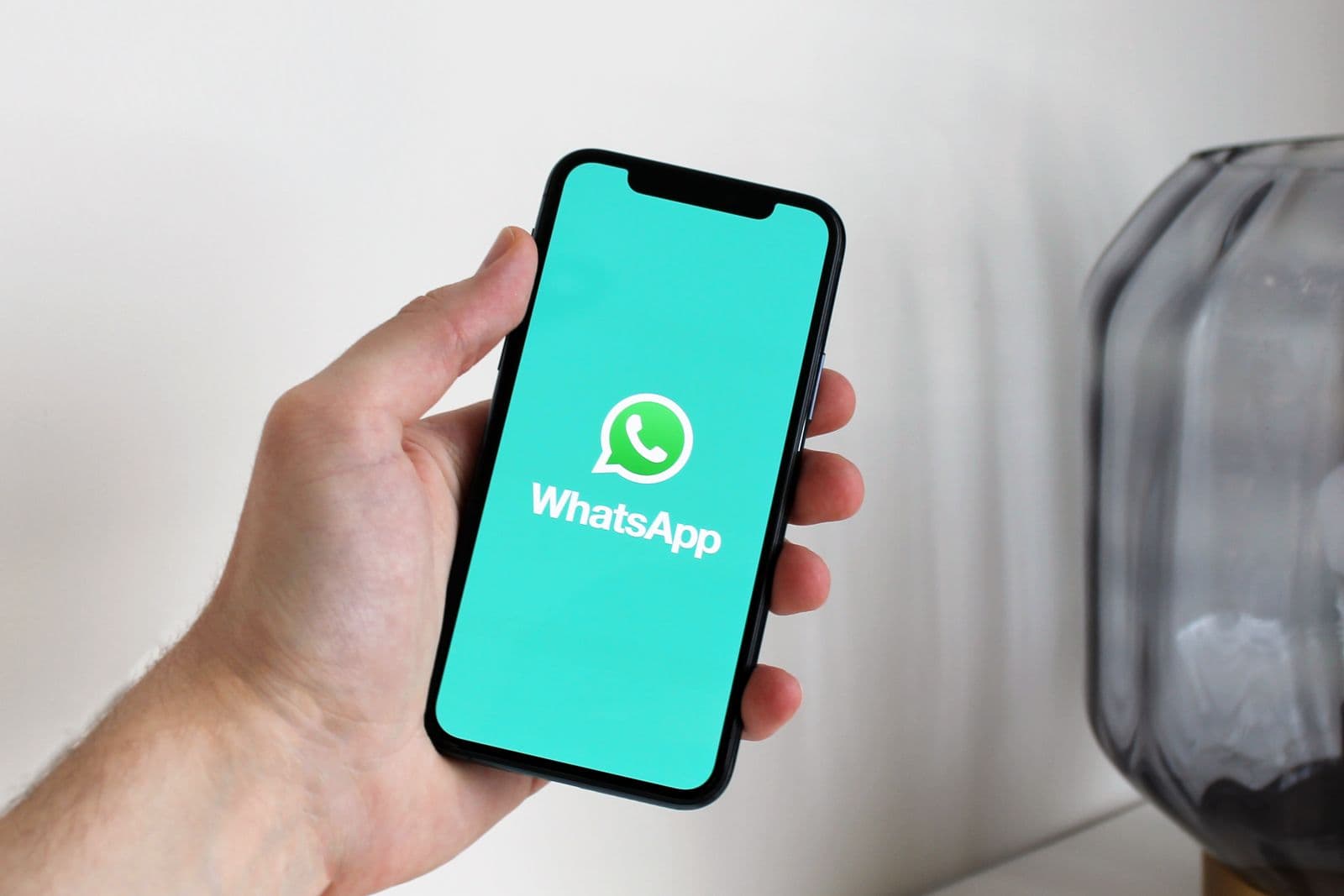 Arab businesswoman using a phone and laptop to manage WhatsApp conversations for a Gulf business