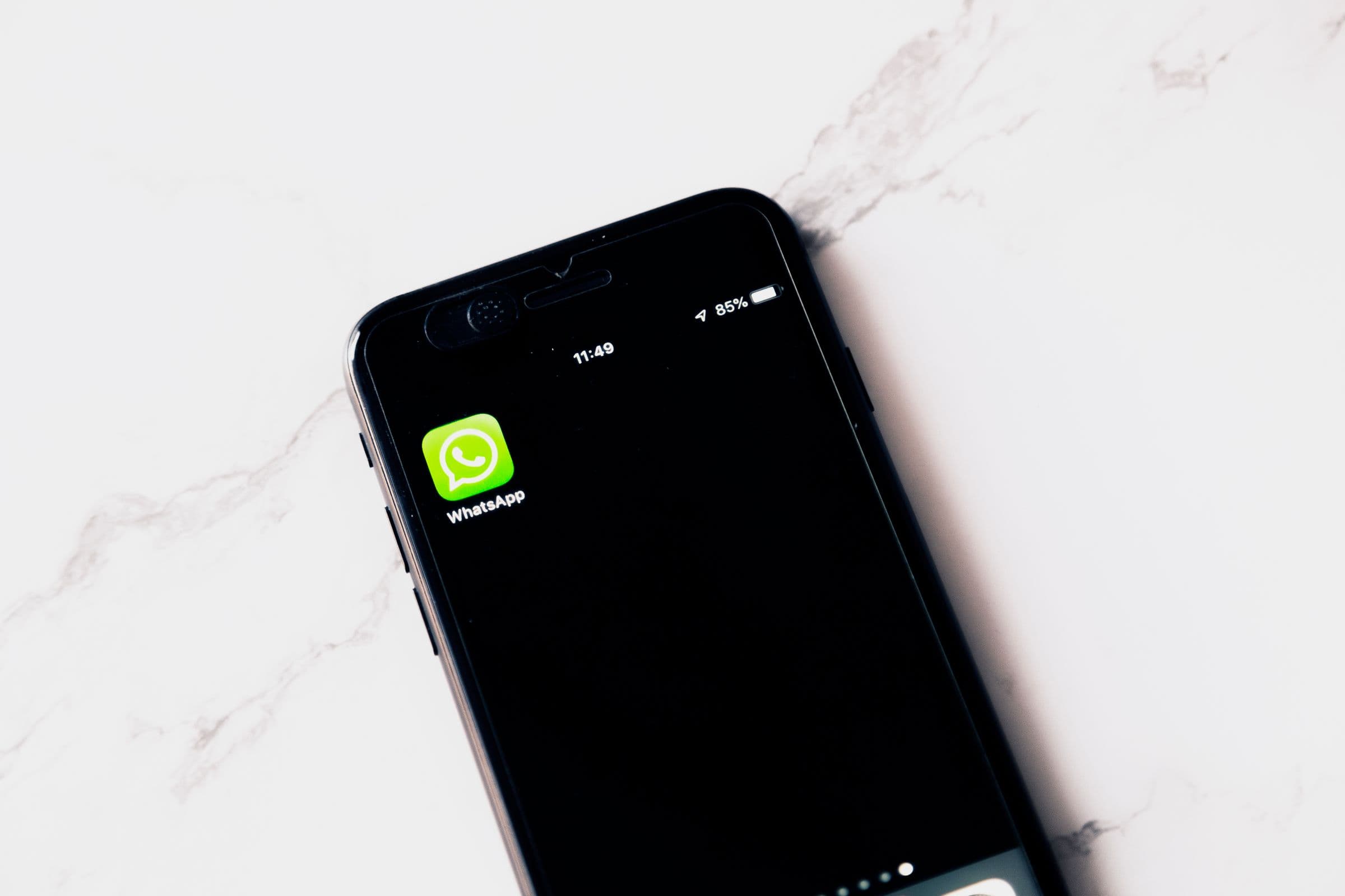 Arab businesswoman using a phone and laptop to manage WhatsApp conversations for a Gulf business