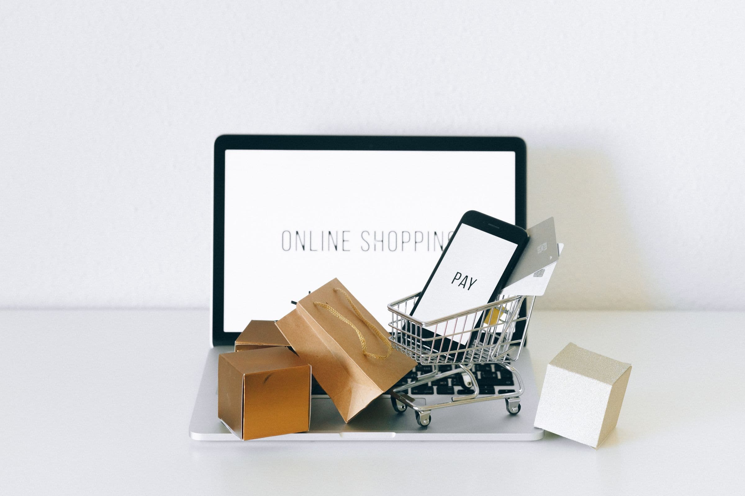 Cart, card, and phone on a laptop representing ecommerce checkout