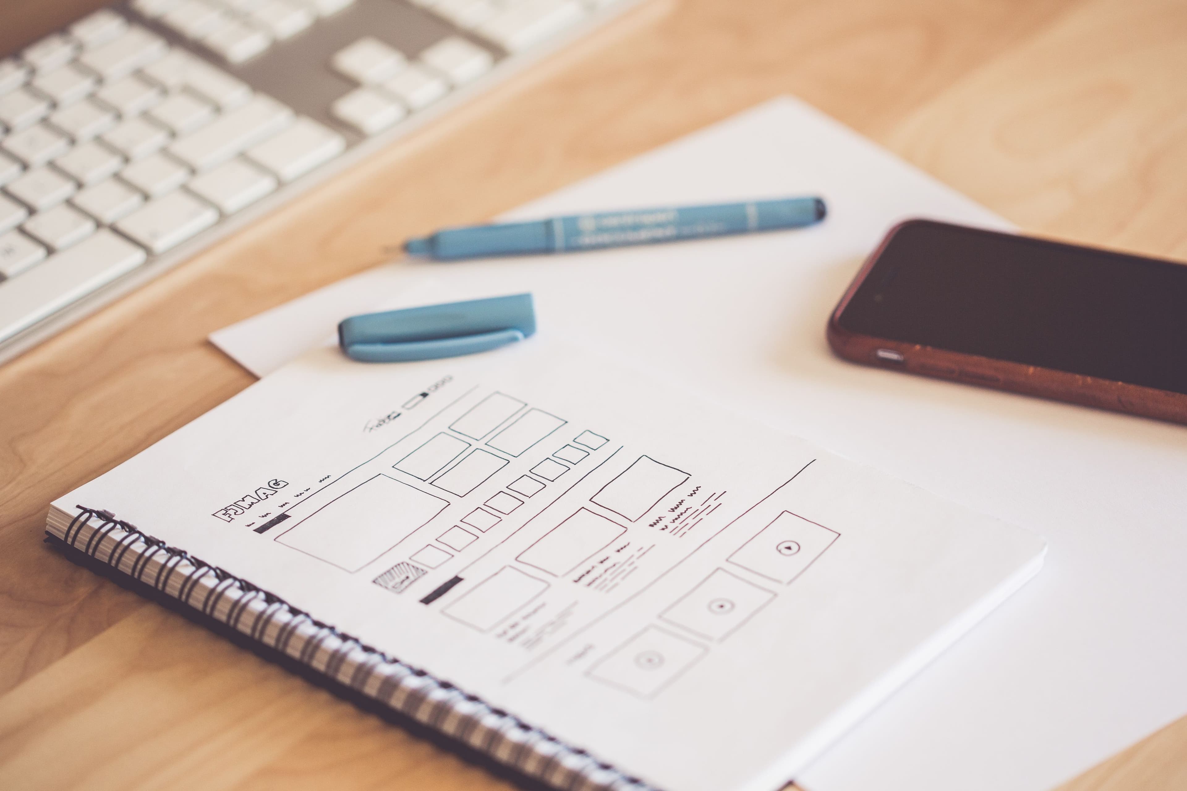 Pen and smartphone on a paper plan for preparing a PRD