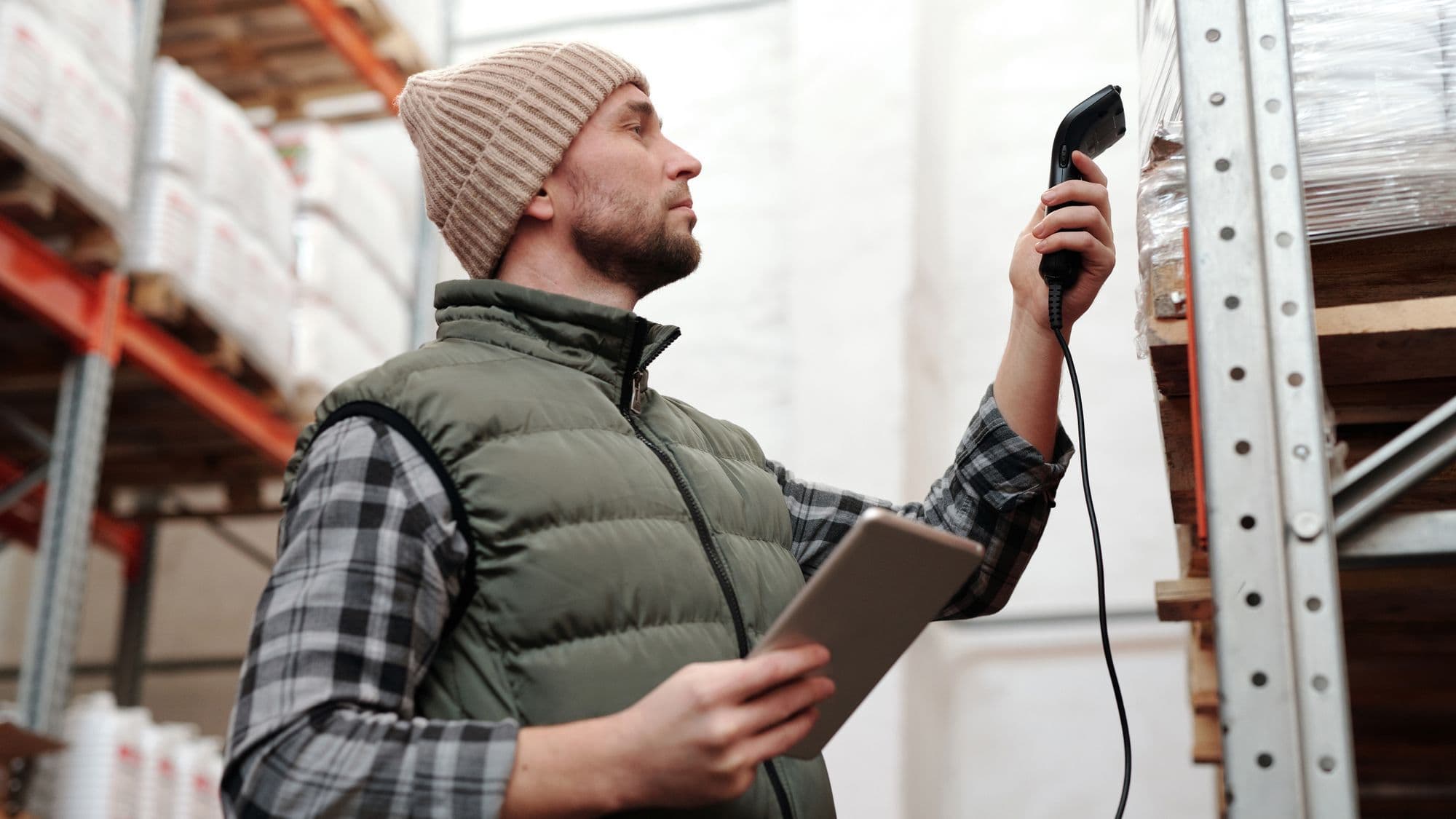 Warehouse employee scanning stock with a handheld device and tablet
