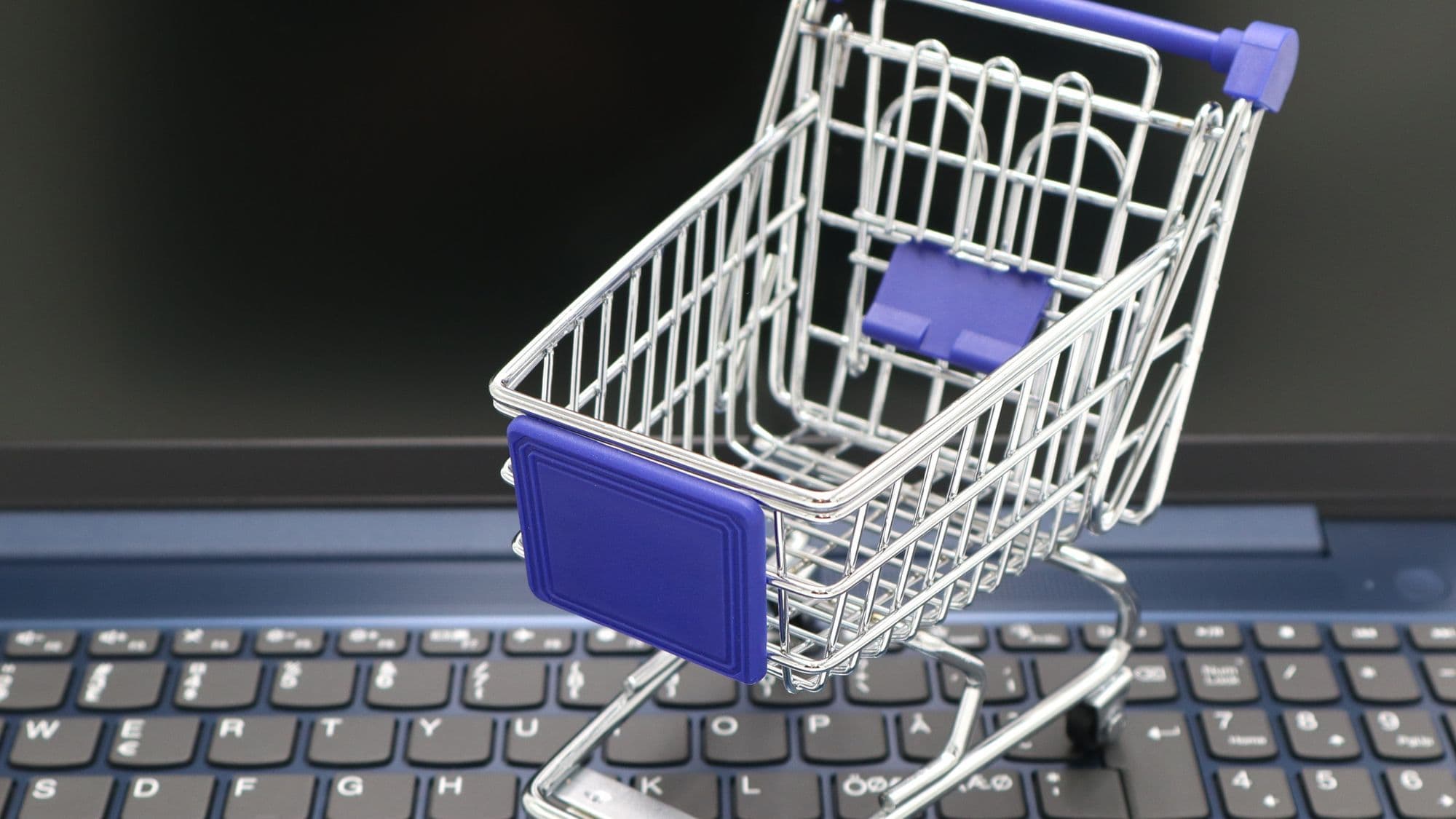 Miniature shopping cart on a keyboard representing ecommerce platform selection