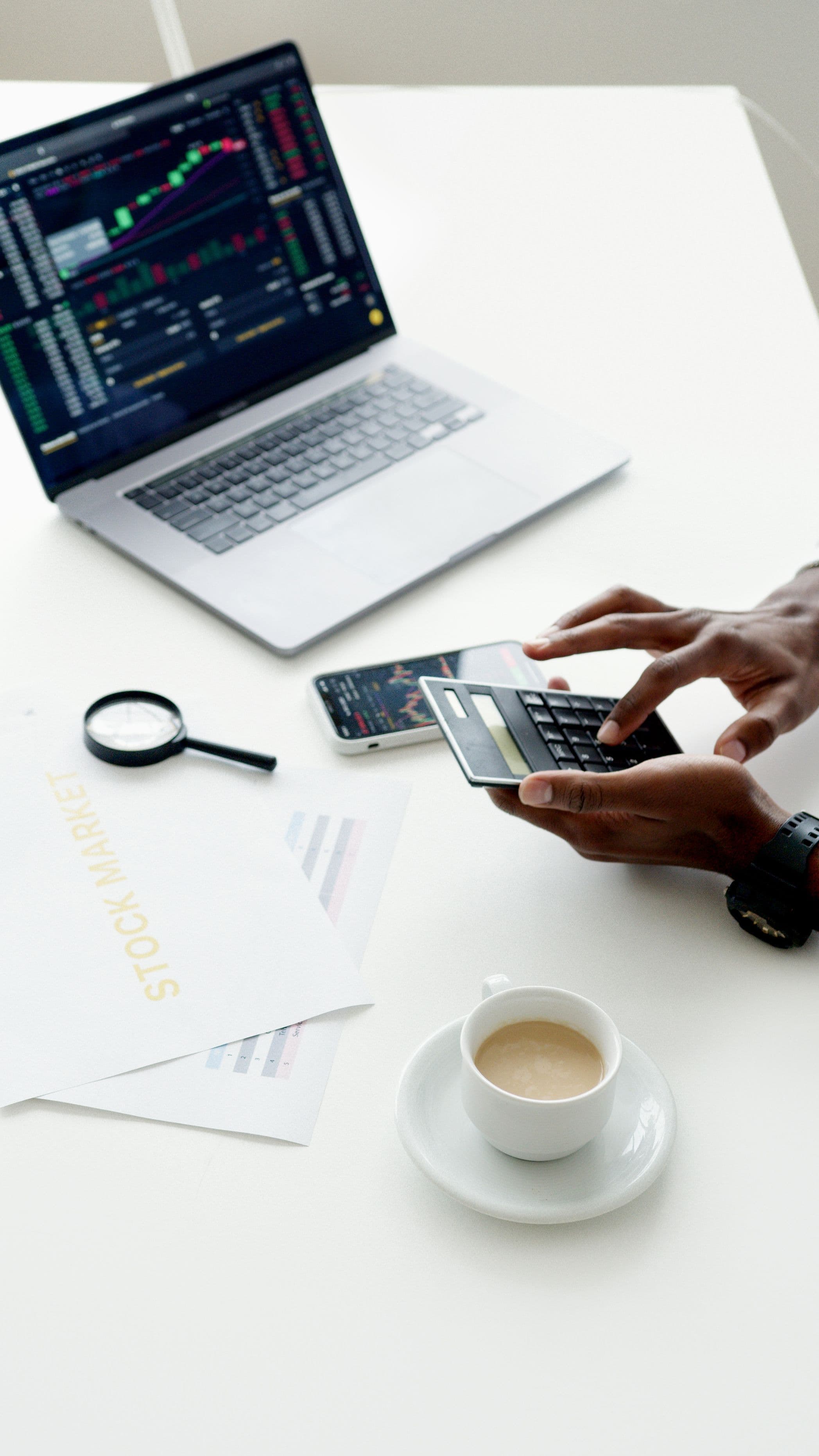 Person calculating a website budget beside a laptop showing data