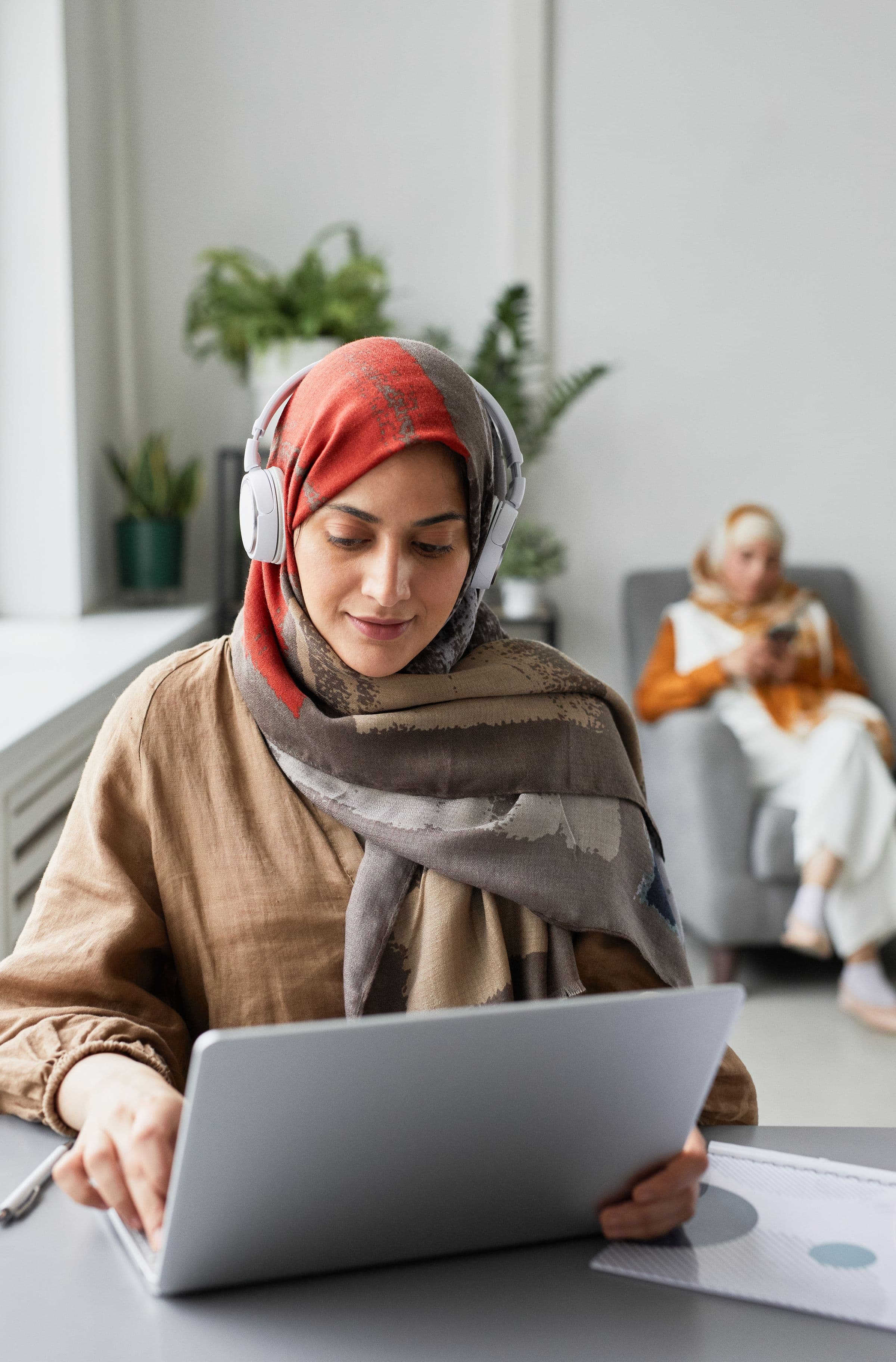 Arab customer support specialist using headphones and a laptop for automated replies